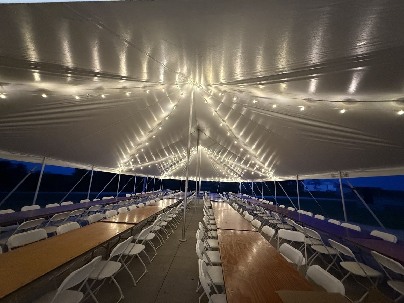 Tent reception setup with string lights at night